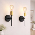 Set of two Ambellina iron armed wall sconces with vintage-style candle holders and intricate design for elegant lighting.