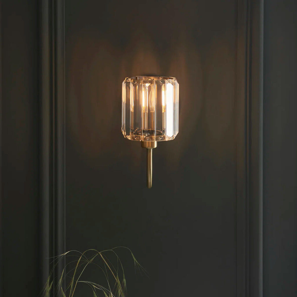 Steel and glass armed sconce by TheChandelierCo featuring a modern design with sleek metal arm and clear glass shade.