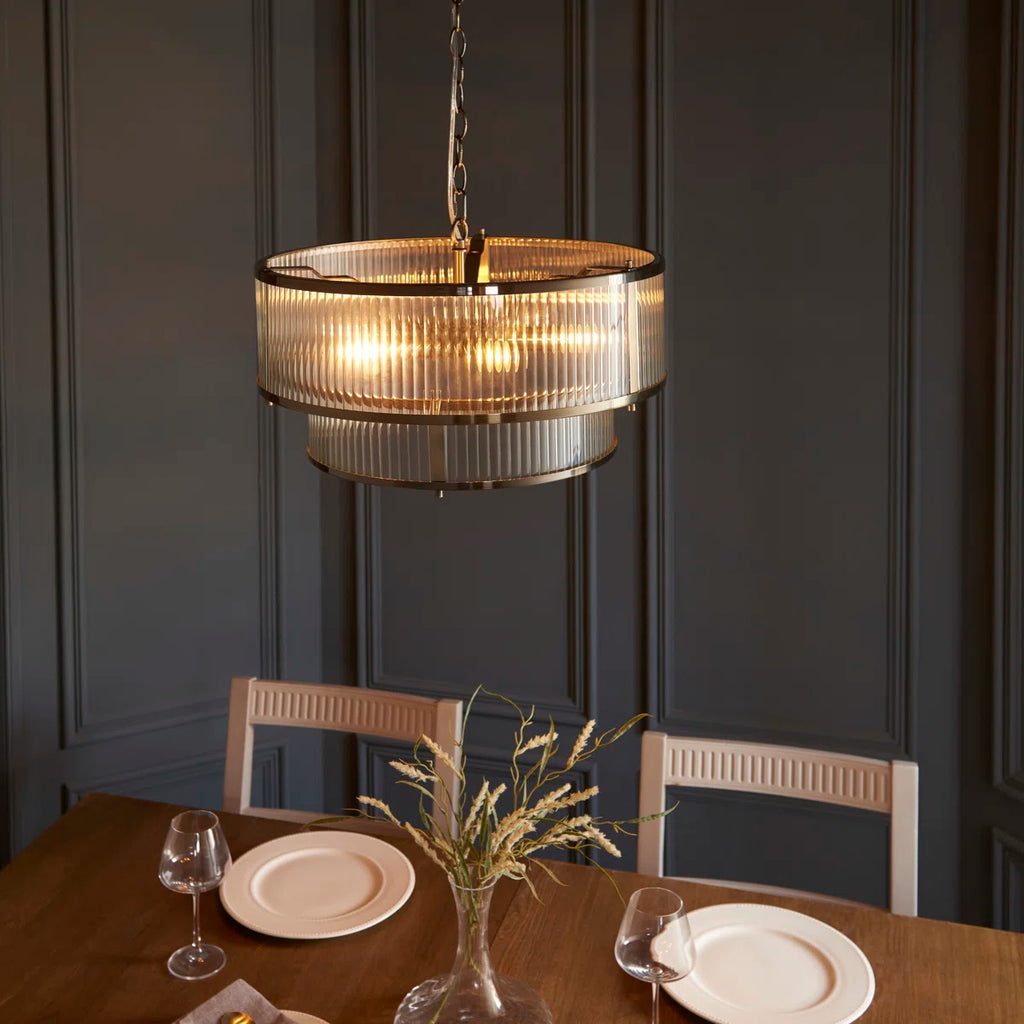 Anesty 5-light pendant chandelier by TheChandelierCo with antique brass finish, featuring sleek metal shades hanging from a central fixture.