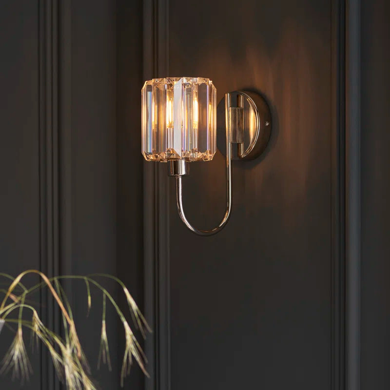 Bright nickel finish steel and glass armed sconce with modern design, featuring a sleek wall-mounted light fixture.