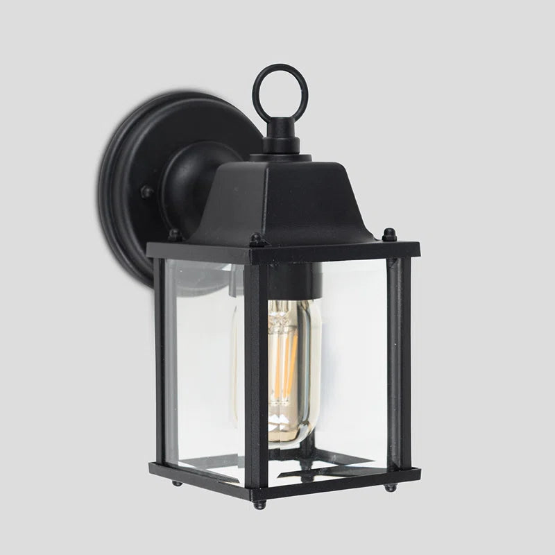 Black outdoor wall lantern by TheChandelierCo, featuring a classic design with clear glass panels and decorative metal details.