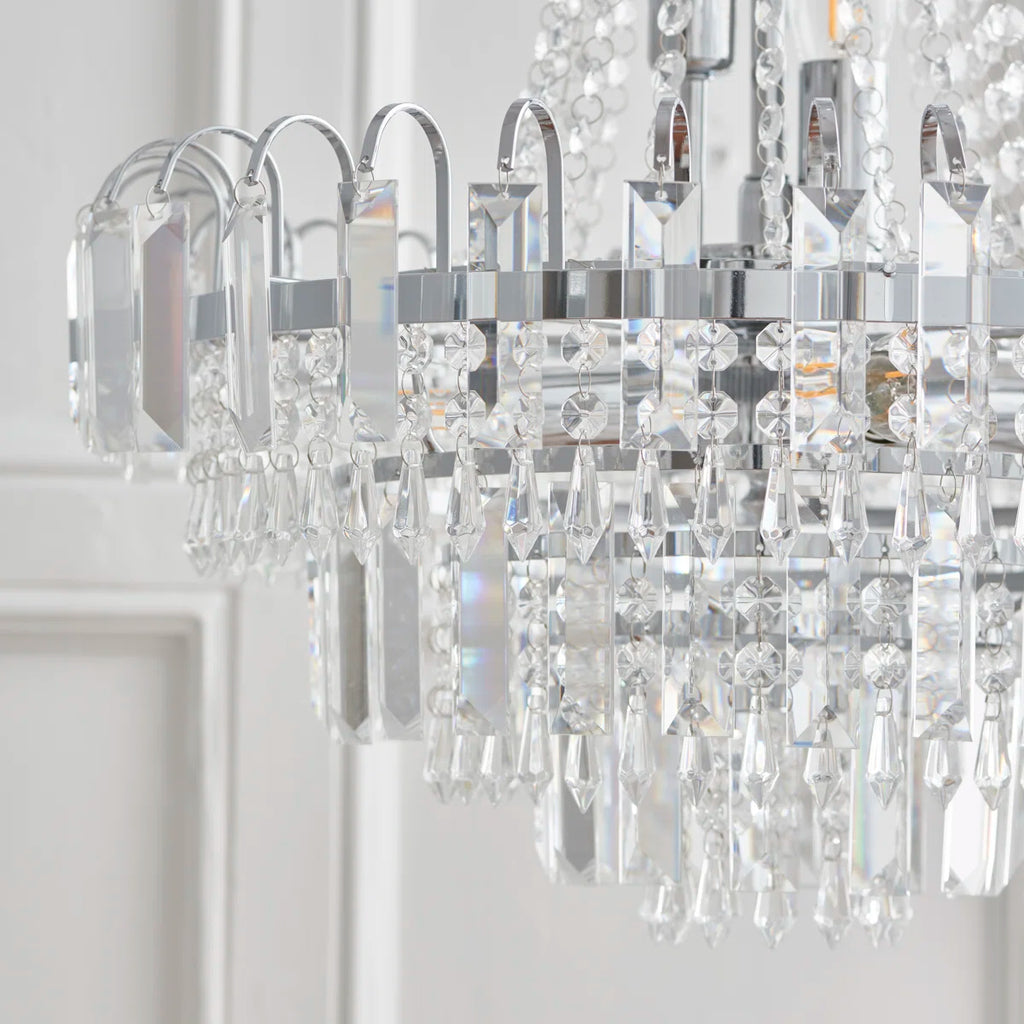 Elegant Jayla 6 light chandelier by TheChandelierCo featuring a modern design with six crystal glass shades and a sleek metallic finish.
