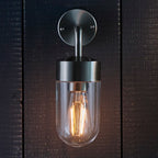 Myla 21cm H outdoor wall lantern by TheChandelierCo features a classic black metal frame and clear glass panels.