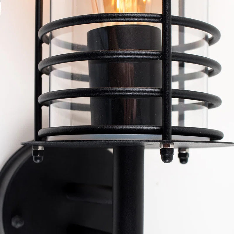 Black outdoor wall lantern with a classic design, featuring clear glass panels and a sturdy metal frame for outdoor lighting.